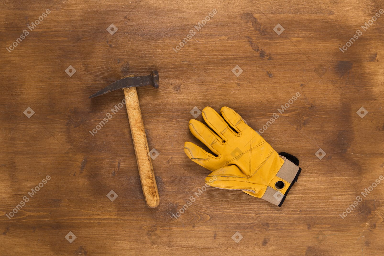 Yellow construction glove and hammer on wooden background