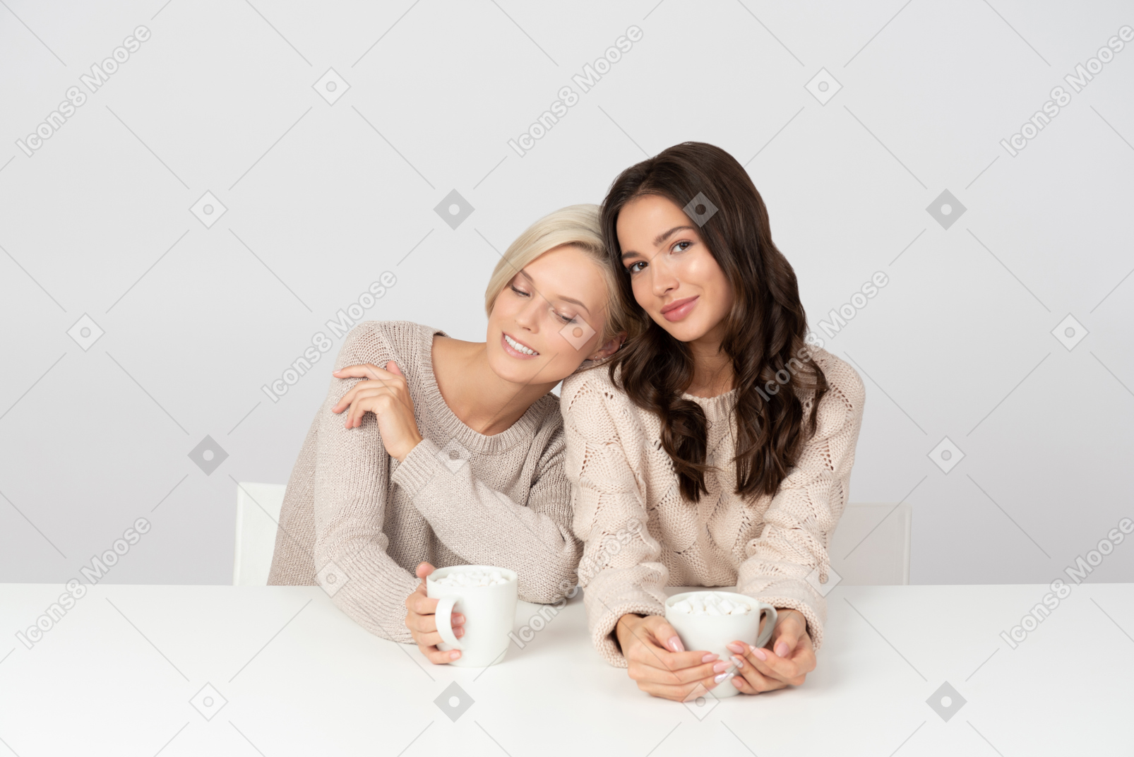 Young women leaning on each other and drinking coffee