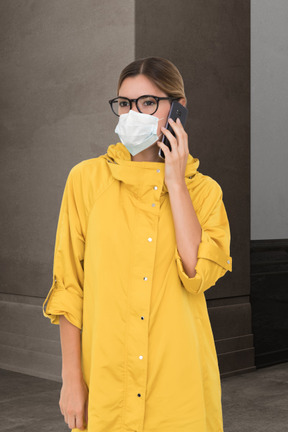 Woman in face mask and rain coat talking on the phone