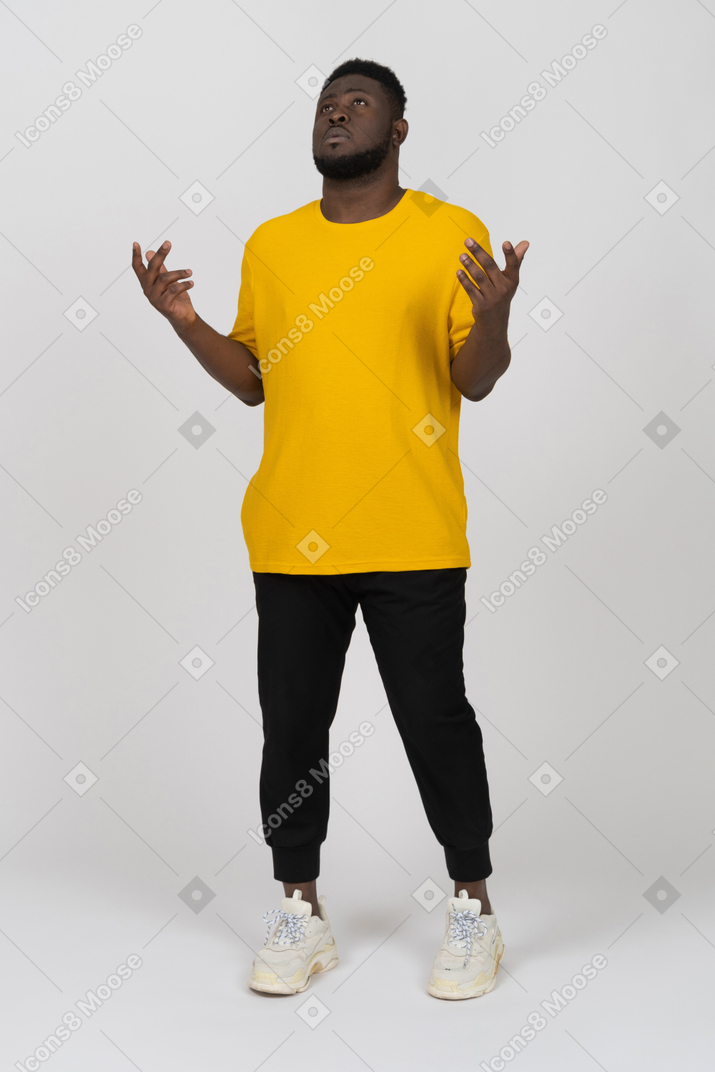 Front view of a young dark-skinned man in yellow t-shirt standing still