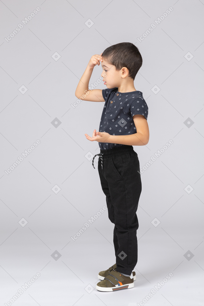 Side view of a boy in casual clothes posing with hand on head