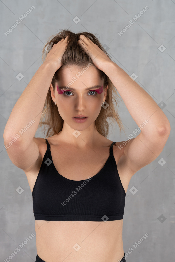 Portrait of a young woman pulling her hair up in ponytail