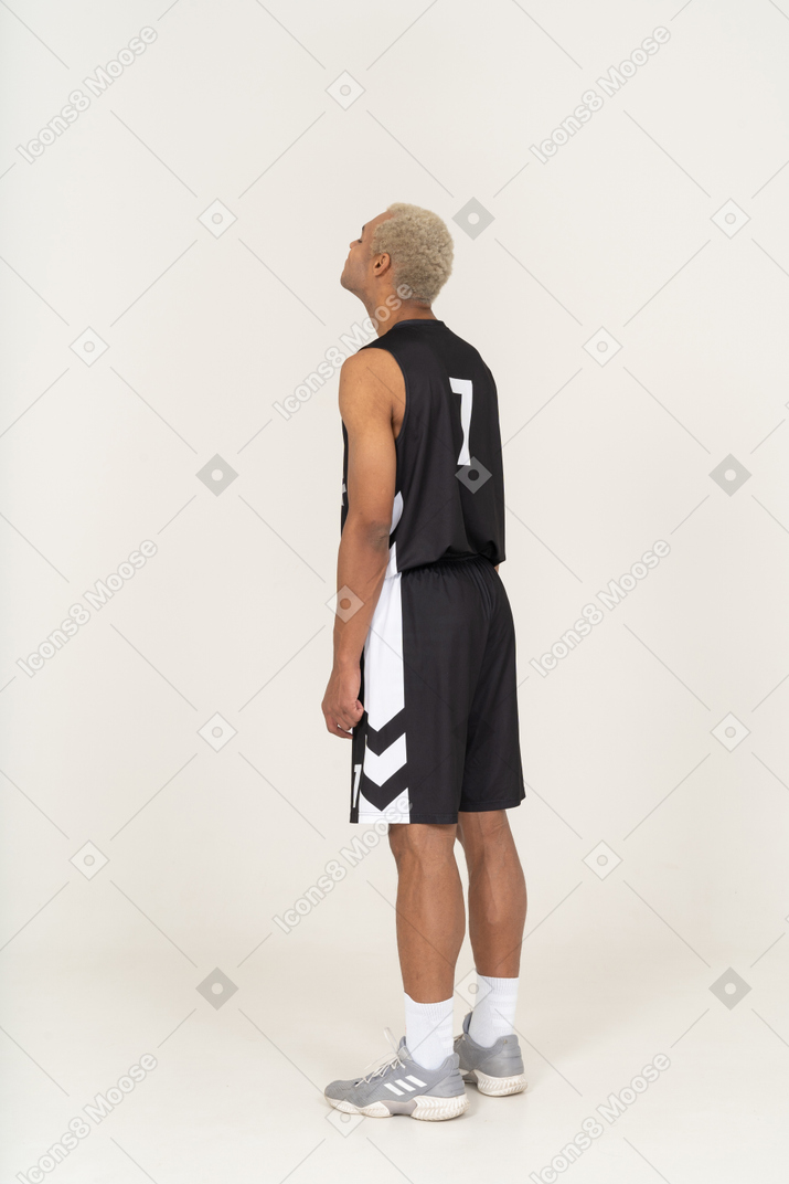 Vista posteriore di tre quarti di un giovane giocatore di basket maschio che alza la testa