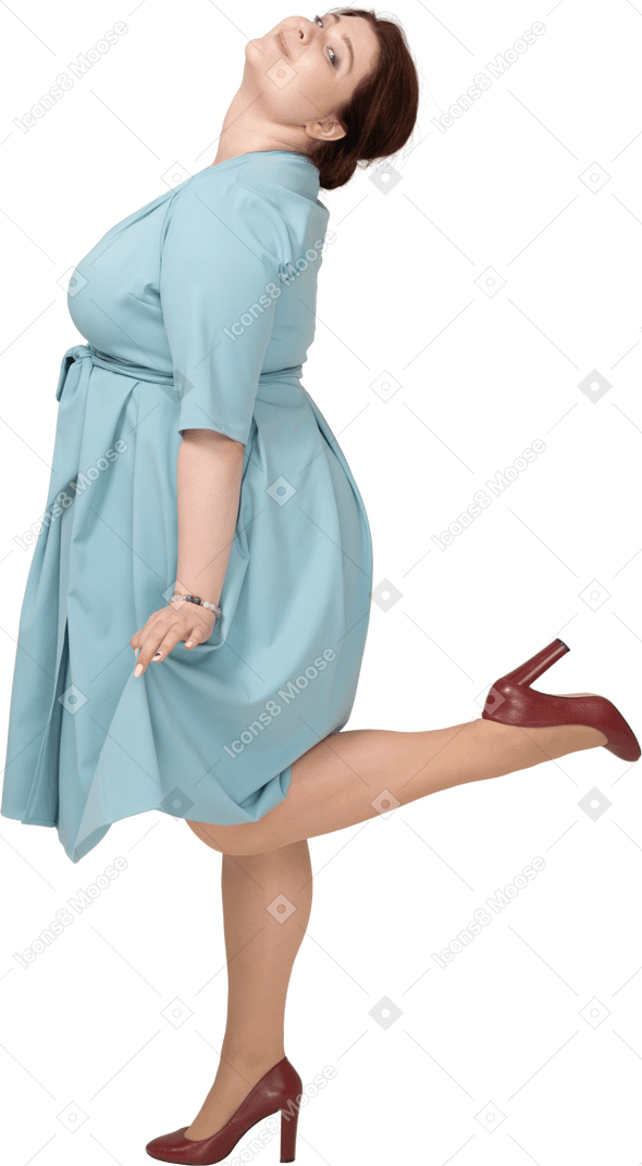 Vue latérale d'une femme en robe bleue debout sur une jambe