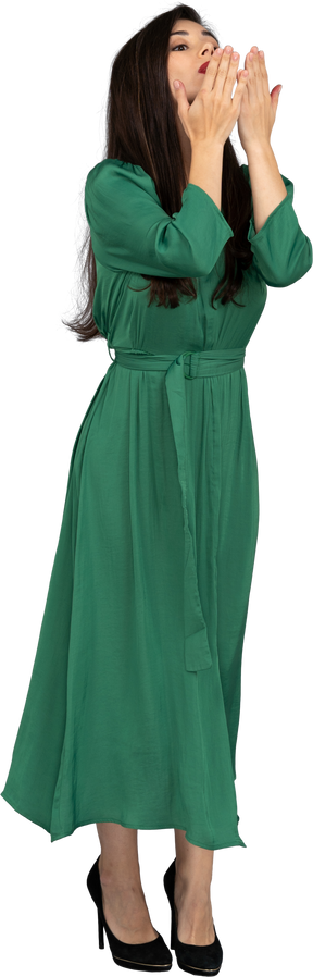 공기 키스를 보내는 녹색 드레스를 입은 젊은 아가씨의 3/4보기