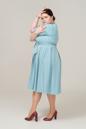 Vista lateral de uma mulher de vestido azul posando