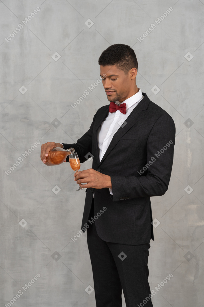 Homem com roupa formal despejando espíritos em um copo de flauta
