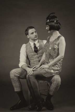 Retro-styled portrait of a beautiful lady sitting on gentleman`s knees