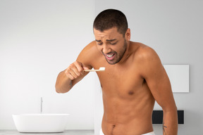 A man brushing his teeth in front of a bathroom