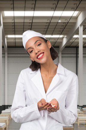 Smiling woman in a white lab coat holding pills