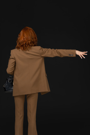 Back view of a woman in a brown suit hailing a cab