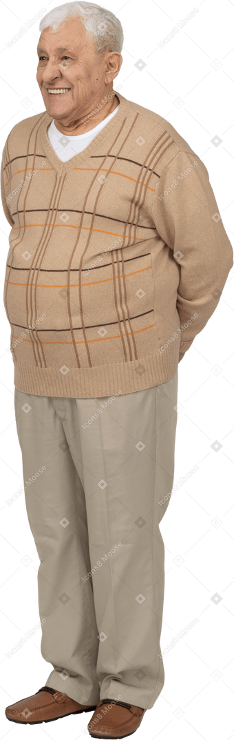 一个穿着休闲服、双手背在身后站着的快乐老人的正面图