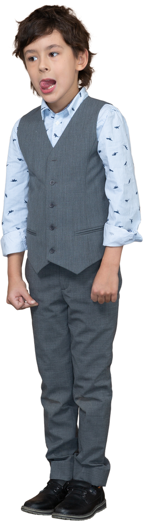 Vista frontal de un chico lindo en traje gris mirando a la cámara y mostrando la lengua