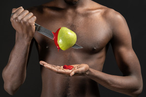 Close-up a man piercing an apple with a ketchup