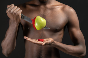 Nahaufnahme ein mann, der einen apfel mit einem ketchup durchbohrt