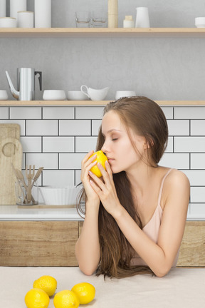 A young woman holding a lemon close to her face