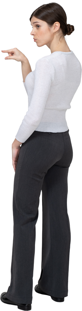 Vista posteriore di tre quarti di una giovane donna in abiti da ufficio che mostra le dimensioni di qualcosa