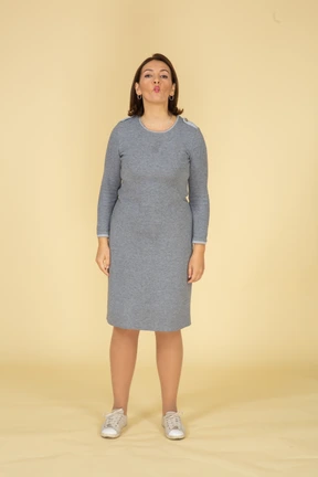 Front view of a woman in grey dress blowing a kiss