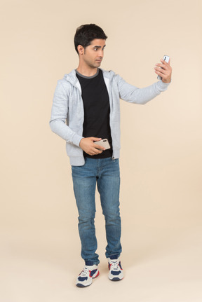 Jovem homem caucasiano segurando um smartphone e olhando em outro
