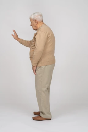 Vista lateral de un anciano con ropa informal que muestra un gesto de parada