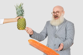 Excited man looking at carrot and pineapple