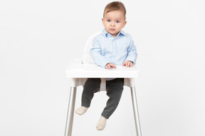 Adorable baby boy sitting in highchair