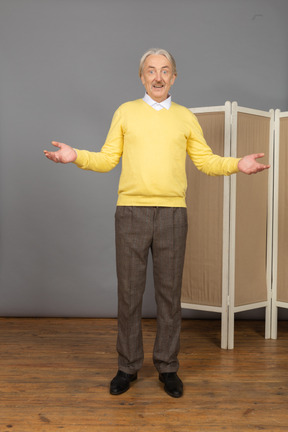 Vista frontal de un anciano sonriente cerca de la pantalla levantando las manos