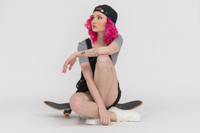 A teenage girl sitting on a skateboard