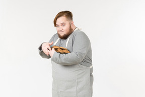 A fat man holding tight plate of cookies