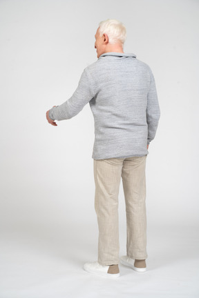 Rear view of a man standing and reaching out his left arm