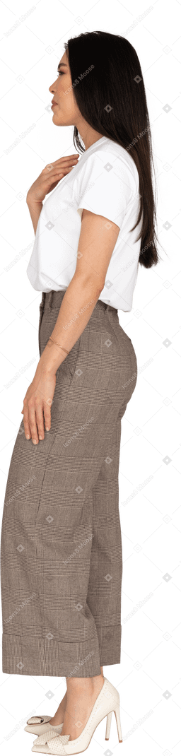 Vue latérale d'une jeune femme en culotte et t-shirt touchant sa poitrine