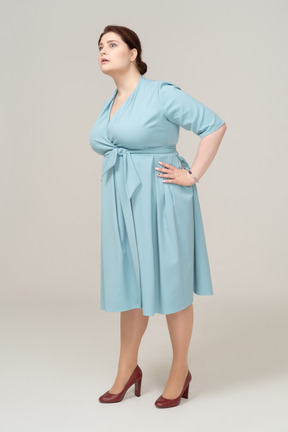 Vista frontale di una donna in abito blu in posa con la mano sull'anca