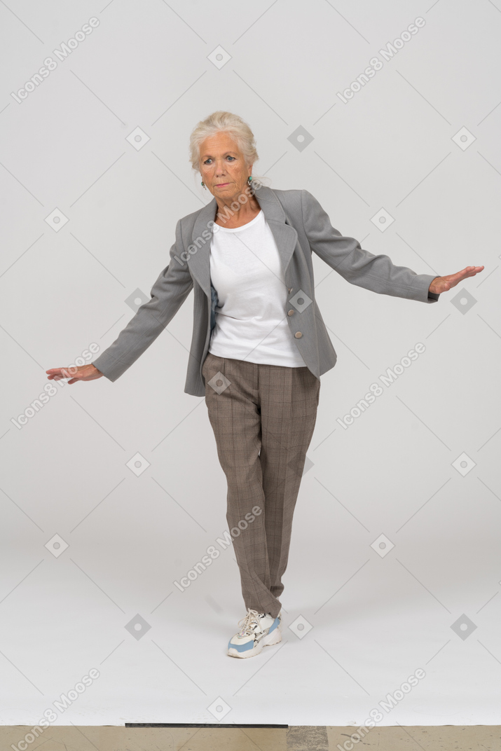 Vorderansicht einer alten dame im anzug, die mit ausgestreckten armen steht