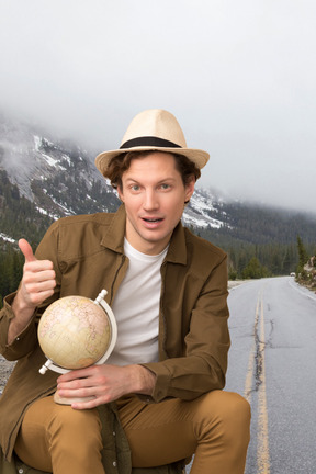 A man in a hat is holding a globe