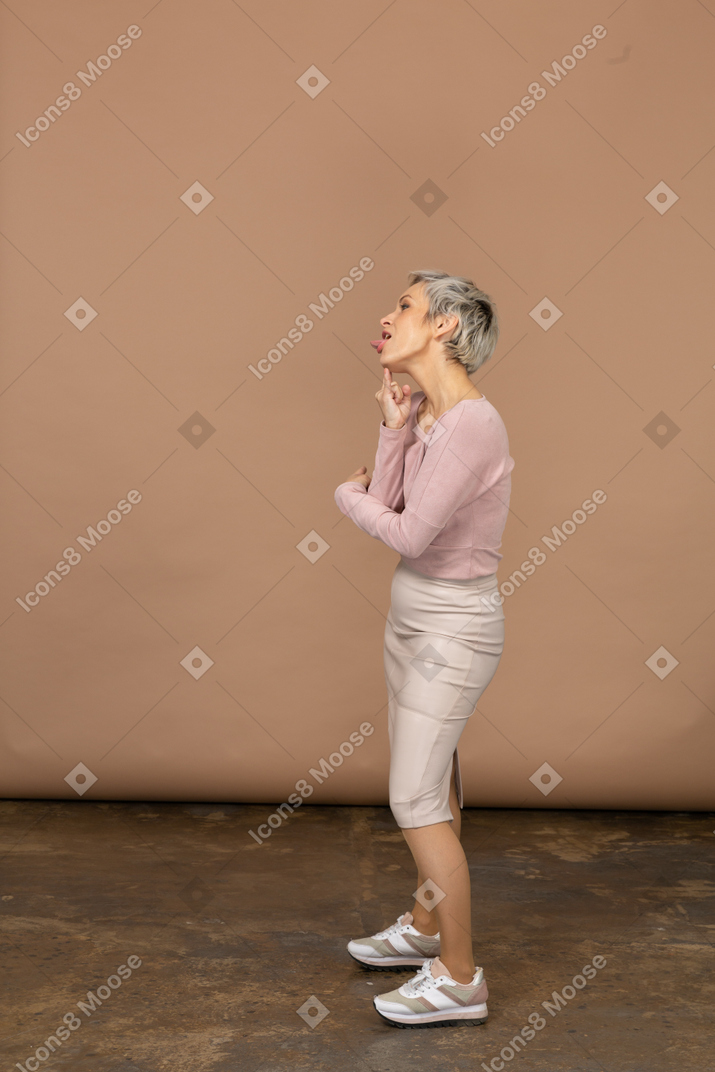 Vista lateral de uma mulher com roupas casuais fazendo caretas