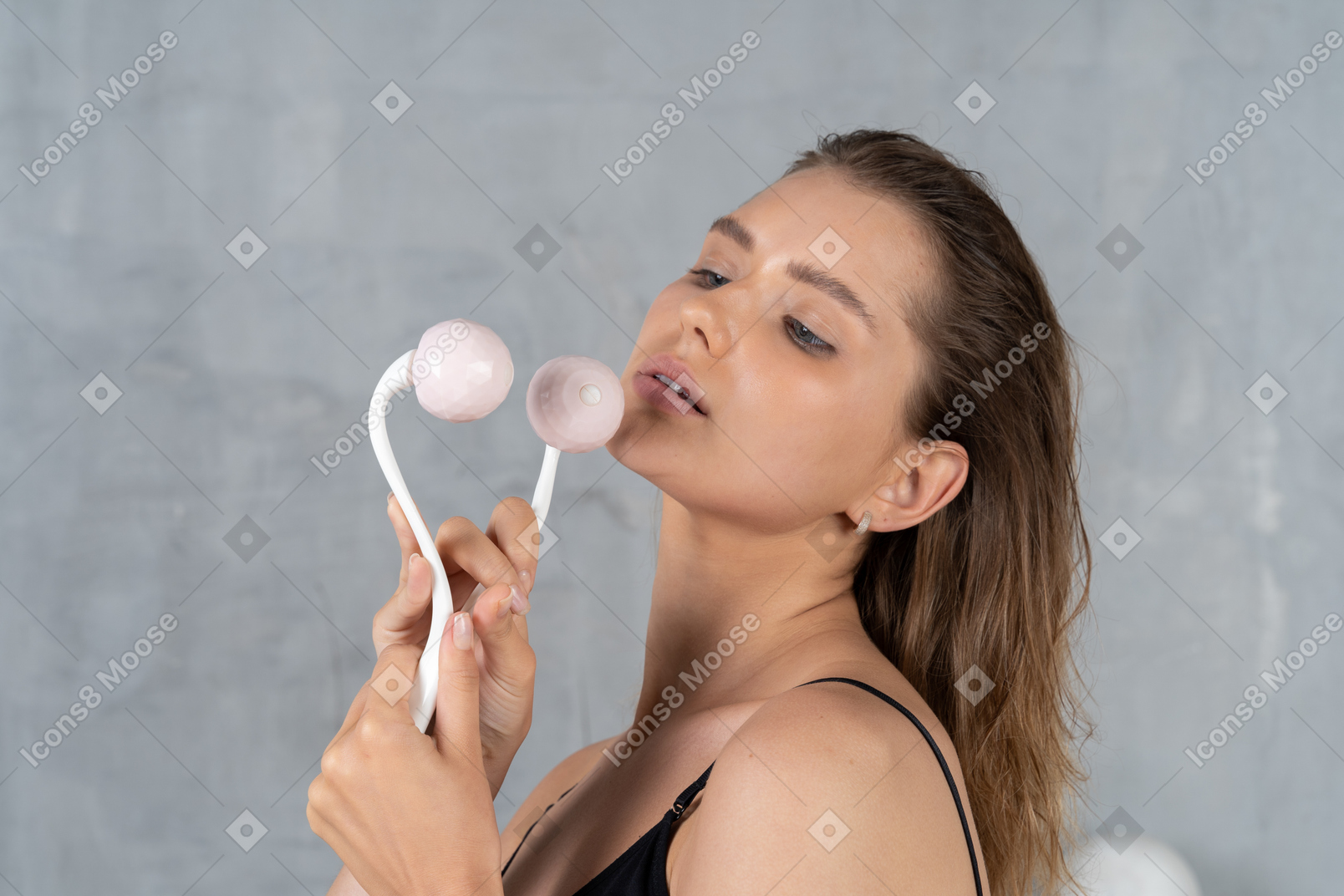 Portrait of a young woman holding facial massager