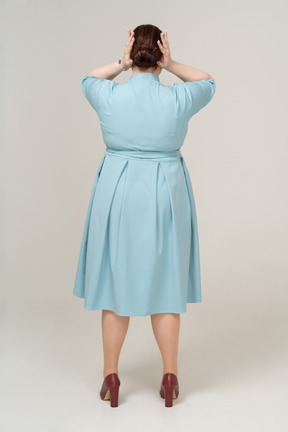 手で目を覆う青いドレスを着た女性の背面図