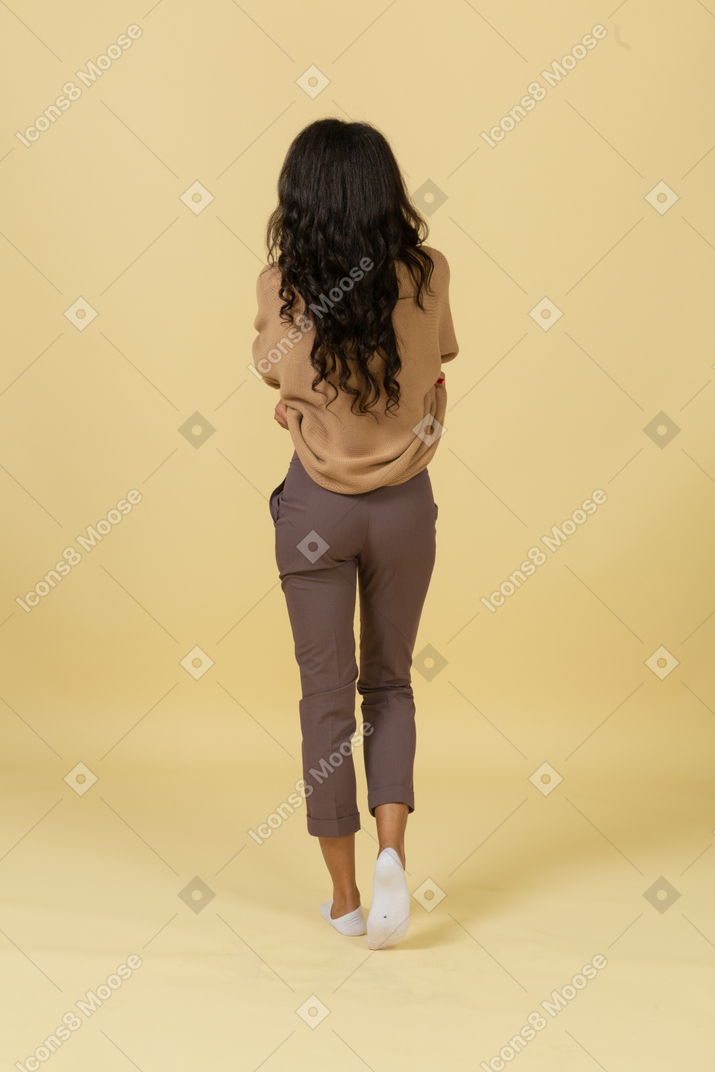 彼女のプルオーバーを脱いでいる浅黒い肌の若い女性の背面図