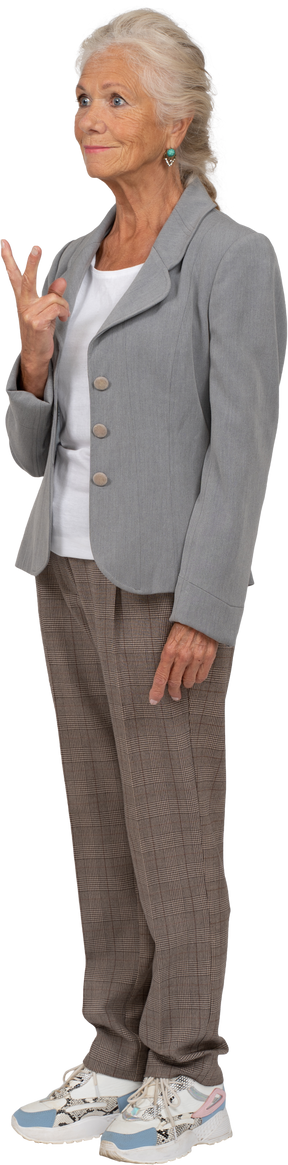 Side view of an old lady in suit showing v sign