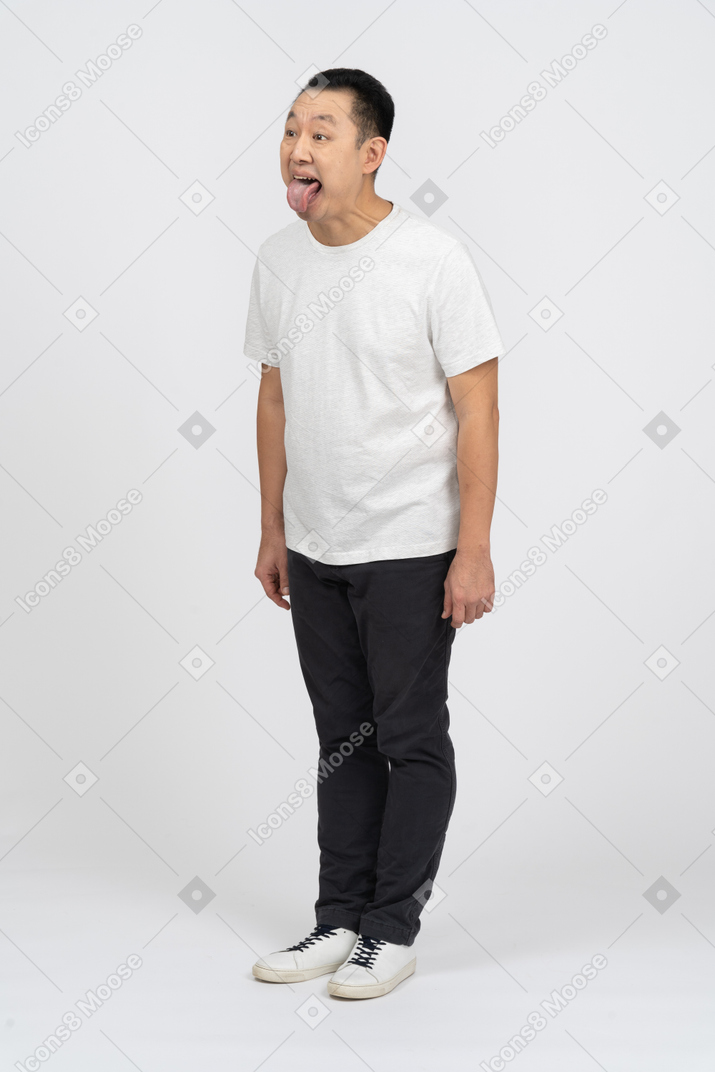 Man in casual clothes making funny face and showing tongue
