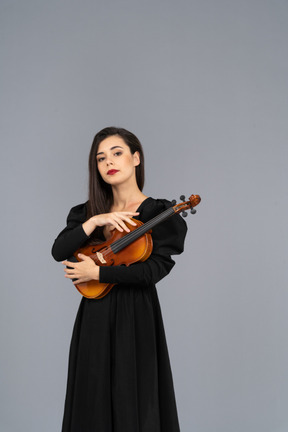 Vista frontal de uma jovem de vestido preto segurando o violino