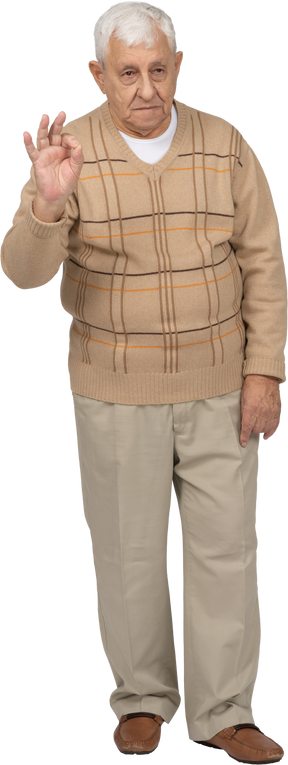 Vista frontal de um velho em roupas casuais, mostrando sinal de ok