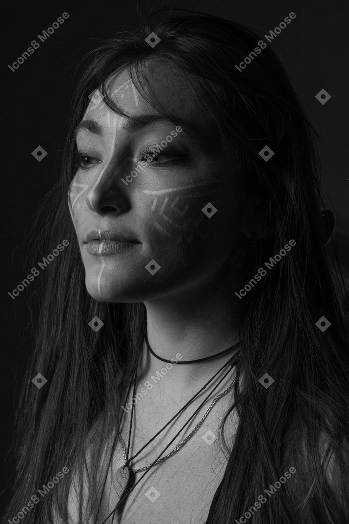 Foto noir de vista lateral de uma jovem com arte no rosto olhando de lado
