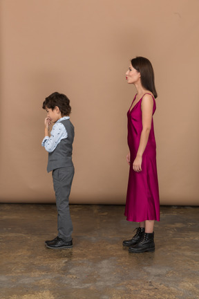 Mulher com vestido vermelho e menino com colete cinza no perfil