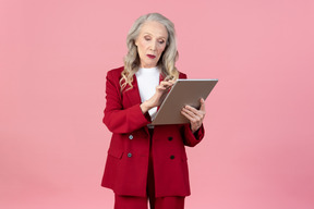Mujer de oficina envejecida usando una tableta digital