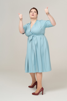 Front view of a happy woman in blue dress dancing