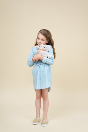 Милая маленькая девочка держит плюшевого мишку