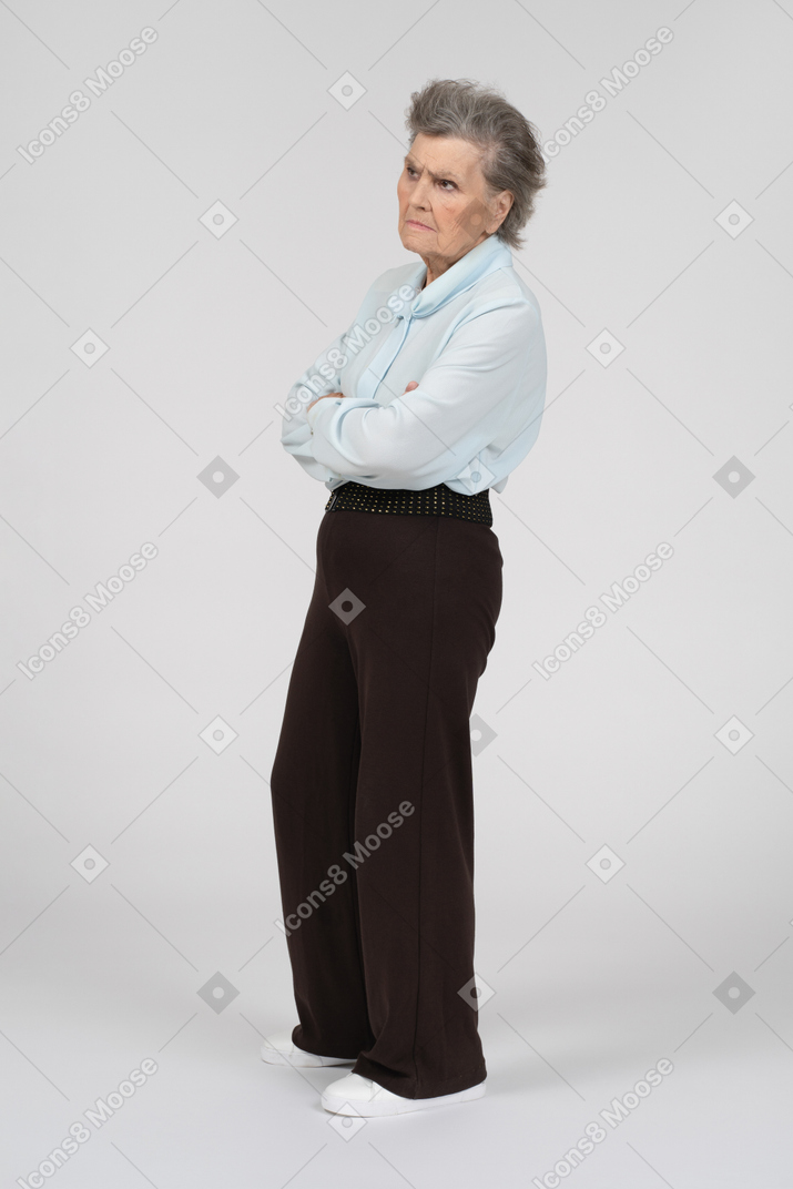 Side view of an old woman frowning suspiciously with folded hands