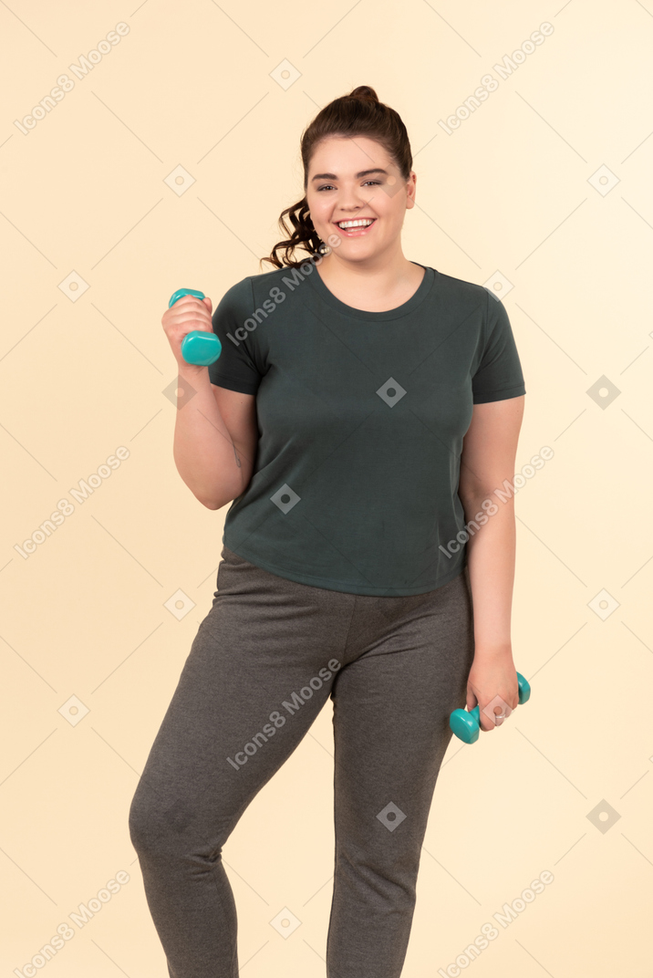 Молодая женщина больших размеров в спортивной одежде делает физические упражнения