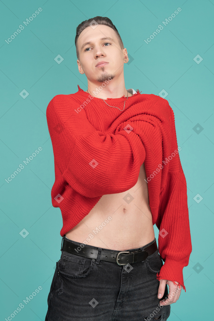 Seguro joven levantando su suéter rojo